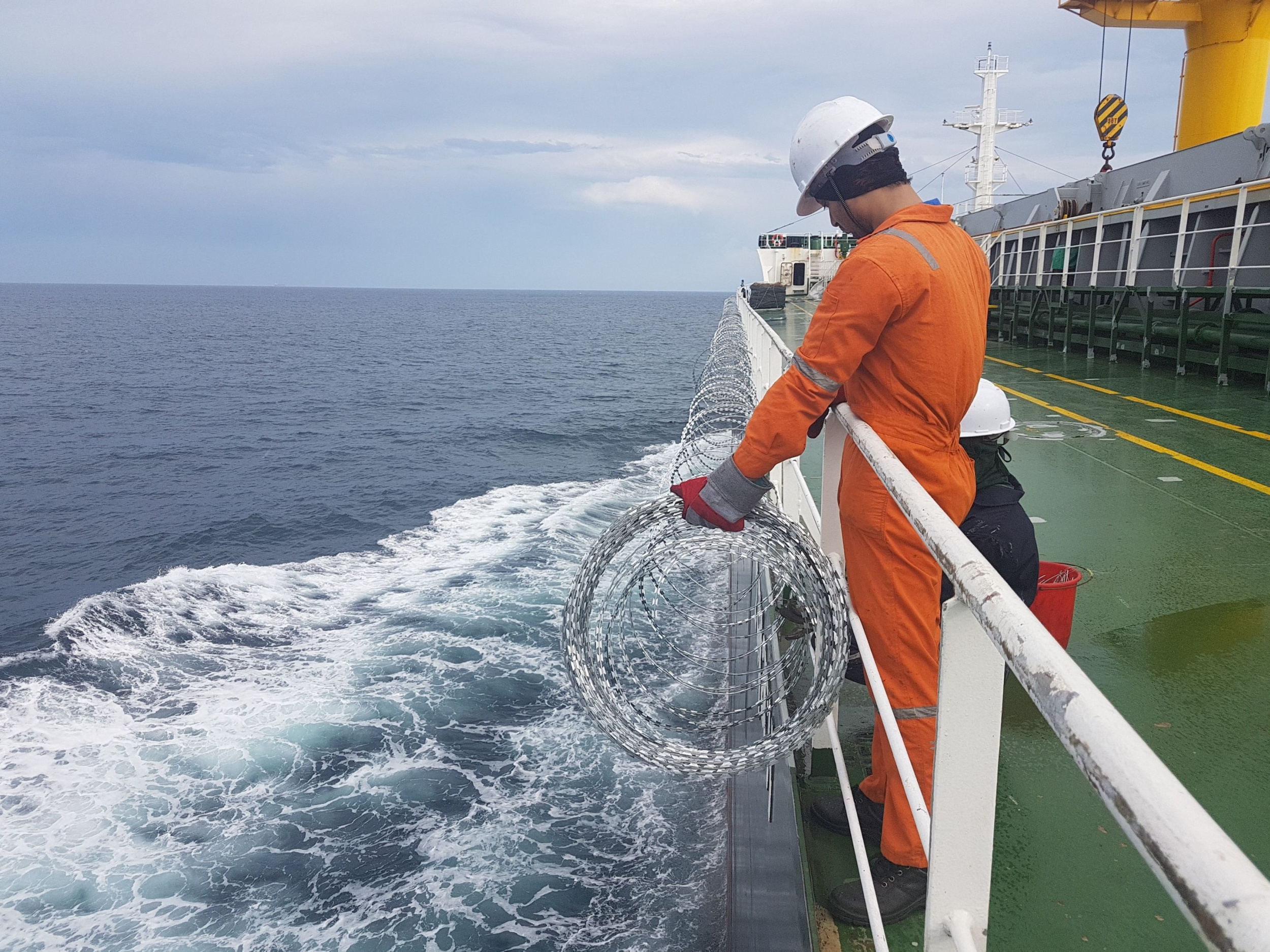 Członek załogi statku instaluje drut kolczasty na burcie, aby chronić się przed atakiem pirackim podczas tranzytu przez Morze Czerwone
